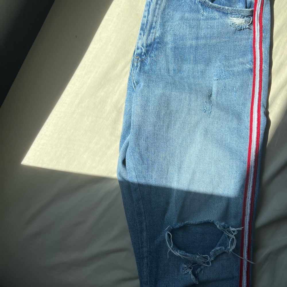 Distressed Light blue denim mom jeans with red and white details on the side.